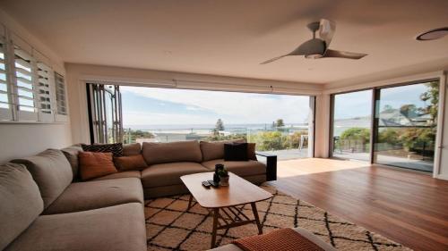a living room with a couch and a table at The Pool House - Light and Spacious in Wamberal