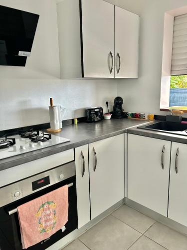 a kitchen with white cabinets and a stove and a sink at Villa Pacifico avec spa in Baillif