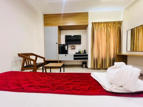 a bedroom with a red bed and a living room at Hotel Sunlight in Puducherry