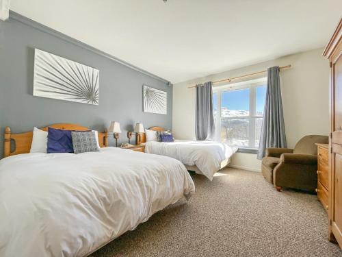 a bedroom with two beds and a chair and a window at 7 Guests 2BR 2BA Pool Hot Tub & Game Room at CBL in Brian Head