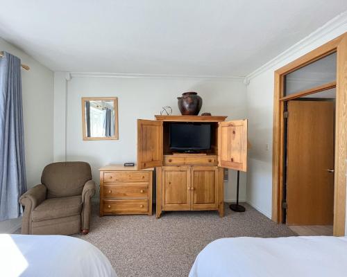a bedroom with a tv and a chair and a cabinet at 7 Guests 2BR 2BA Pool Hot Tub & Game Room at CBL in Brian Head