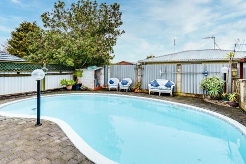 a swimming pool in a yard with two chairs at Sunny Family Haven with Pool in Napier