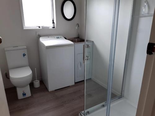 a small bathroom with a toilet and a shower at Sunny Family Haven with Pool in Napier