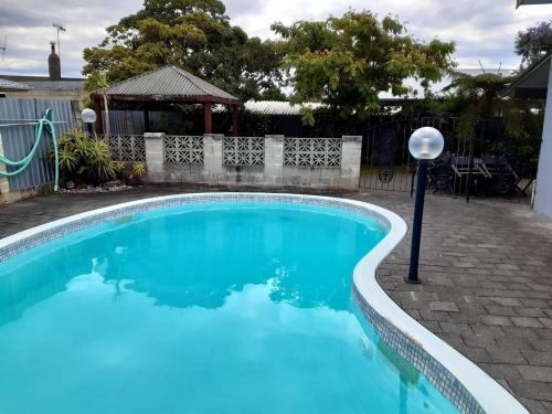 a swimming pool with blue water in a yard at Sunny Family Haven with Pool in Napier