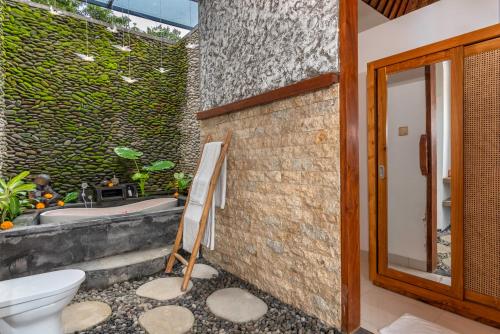 a bathroom with a bath tub and a toilet at The Alus Villa and Suite in Ubud