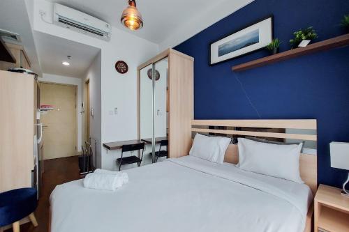 a bedroom with a large bed with a blue wall at Nice and Elegant Studio at Tree Park City BSD Apartment By Travelio in Tangerang