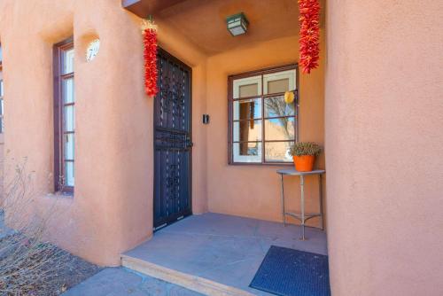 a front door of a house with red flowers on it at Casita Gomez- Courtyard - Quiet - Railyard - 1BR in Santa Fe