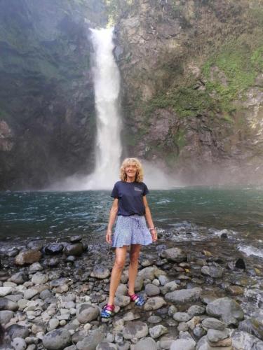 a woman standing on rocks in front of a waterfall at Las vegas lodge and restaurant in Banaue