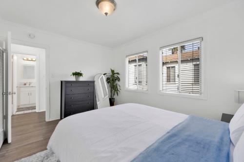 a white bedroom with a bed and two windows at Cozy, Luxurious, Oasis, With Free parking in Los Angeles