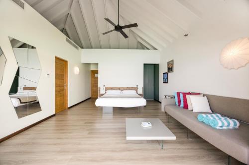 a living room with a bed and a couch at Cocoon Maldives - All Inclusive in Lhaviyani Atoll