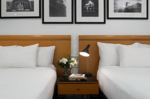 two beds in a hotel room with a side table with flowers at Rydges World Square in Sydney