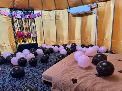 a bunch of balloons on a bed next to a table at Mianfarm Bàu trắng glamping in Ấp Nhơn Hòa