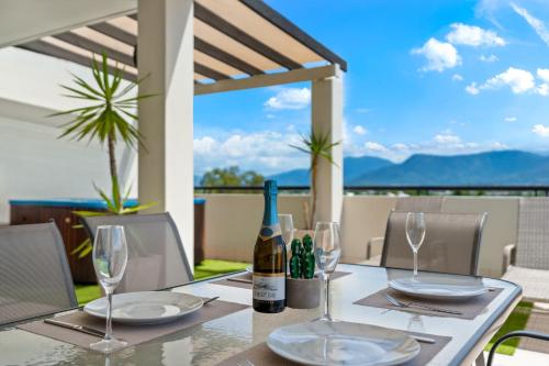 a table with glasses and a bottle of wine at Cairns Penthouse - Private Rooftop Outdoor Gym, Spa & TV Area with Sunset & Mountain Views in Cairns