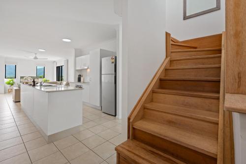 a kitchen and dining room with a staircase in a house at Cairns Penthouse - Private Rooftop Outdoor Gym, Spa & TV Area with Sunset & Mountain Views in Cairns