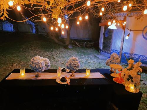 a table with purple hydrangeas and candles and lights at Mianfarm Bàu trắng glamping in Ấp Nhơn Hòa