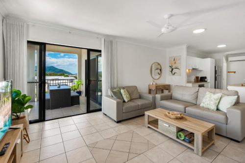 a living room with a couch and a table at Cairns Penthouse - Private Rooftop Outdoor Gym, Spa & TV Area with Sunset & Mountain Views in Cairns