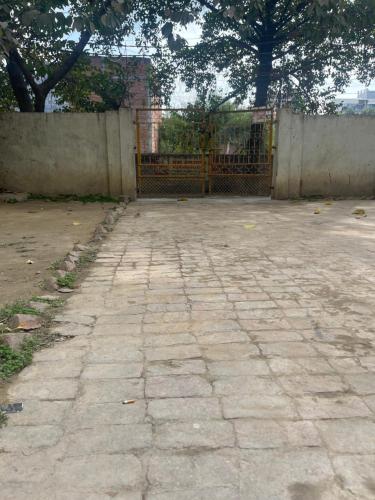 a stone courtyard with a gate and a fence at Yadav multi in Prayagraj