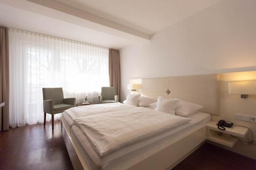 a bedroom with a large white bed and a window at Hotel Seepark Garni in Überlingen
