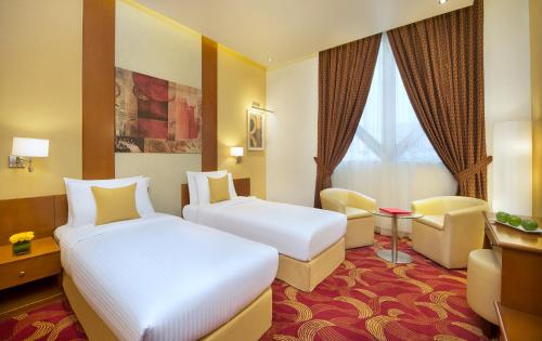 a hotel room with two beds and a chair at City Seasons Towers Hotel Bur Dubai in Dubai
