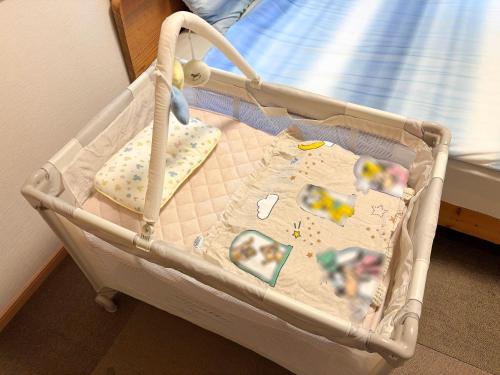 a baby crib with a blanket in a room at 憩いの場　ただいま〜 in Nago