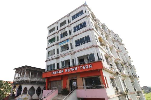 a tall white building with a sign on it at Hotel O Sonu in Tarapith