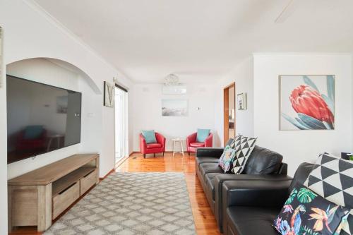 a living room with a couch and a flat screen tv at Bellarine Bungalow - Bay Breezes & Wineries Galore in Portarlington