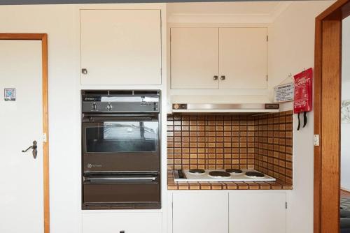 a kitchen with white cabinets and a stove top oven at Bellarine Bungalow - Bay Breezes & Wineries Galore in Portarlington