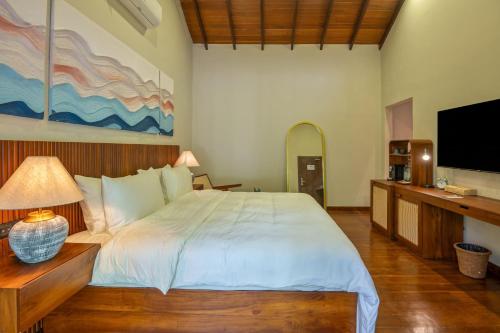 a bedroom with a large bed and a flat screen tv at Arambhaya Boutique Hotel in Kandy