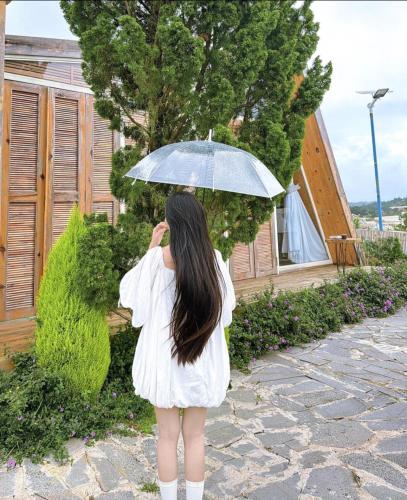 a woman in a white dress holding an umbrella at LayLa Homestay in Lạc Dương