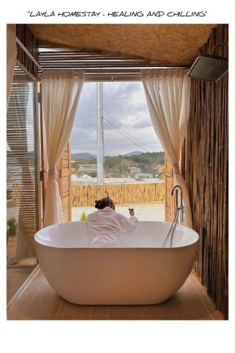 a woman laying in a bath tub in a room with a window at LayLa Homestay in Lạc Dương