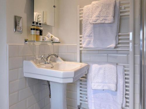 a white bathroom with a sink and towels at Wellwood Manor in Pitlochry