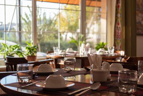 a restaurant with wooden tables and chairs and a large window at Hotel Jipek Joli in Nukus
