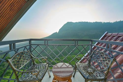 two chairs and a table on a balcony with a view at The Planet Munnar in Suryanelli