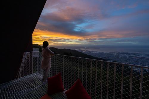 a man standing on a balcony watching the sunset at Nature Live Rokko in Kobe