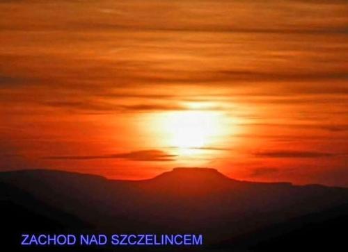 a sunset with the sun setting behind a mountain at Wataha pod Basztami - Wadera - Domki całoroczne in Wünschelburg