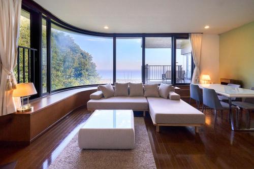 a living room with a couch and a large window at Suite Villa Panora Izu Akazawa 1F in Ito