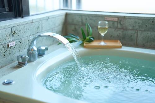 a bath tub with a glass of wine in it at Suite Villa Panora Izu Akazawa 1F in Ito