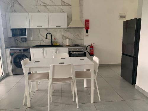 a white kitchen with a white table and chairs at Coco Vanille Chalets in Takamaka