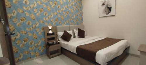 a bedroom with a bed with a blue wall at Hotel Paris Plaza in Ahmedabad
