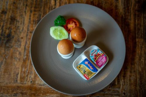 a white plate with eggs and vegetables on a table at Abhirama Villas and Spa in Ubud