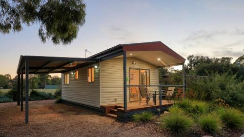 a tiny house with a deck and a table at Yarrawonga Riverlands Tourist Park in Yarrawonga