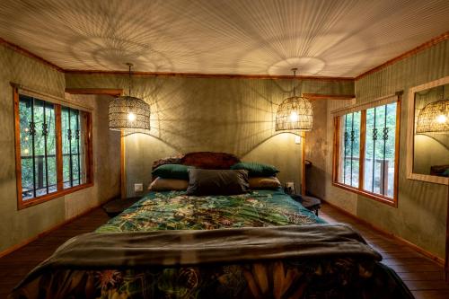 Un dormitorio con una cama grande en una habitación con ventanas. en Matumi Trail Forest Lodges - Matumi and Mitzeeri, en Tzaneen