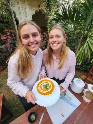 two girls sitting at a table holding a cake at Banana Hostel Pushkar in Pushkar