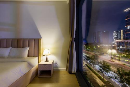 a bedroom with a bed and a window with a city at THE METROPOLE Apartment Complex OPERA-GALLERIA-CREST in Ho Chi Minh City