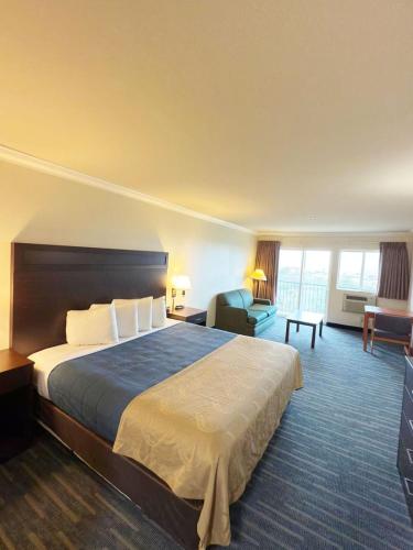 a hotel room with a large bed and a desk at Coratel Inn Ocean Shores Extended Stay in Ocean Shores