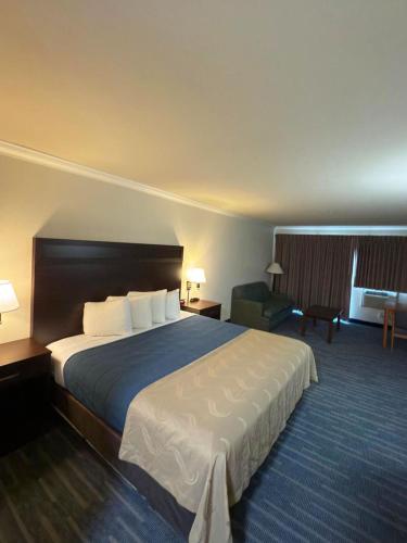 a hotel room with a large bed and a chair at Coratel Inn Ocean Shores Extended Stay in Ocean Shores