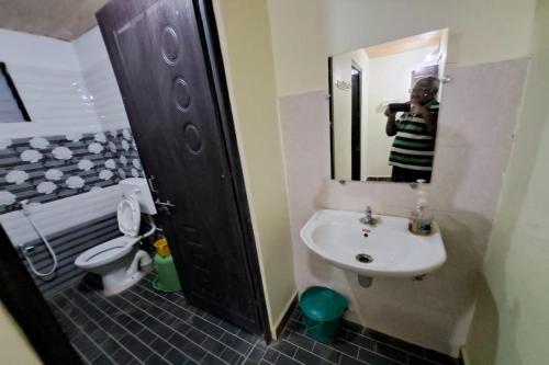 a man taking a picture of a bathroom with a toilet and sink at Cheetah Farms Jungle Stay in Dandeli