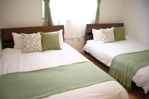a bedroom with two beds with green and white pillows at Casa Stella 17 by Liaison in Osaka