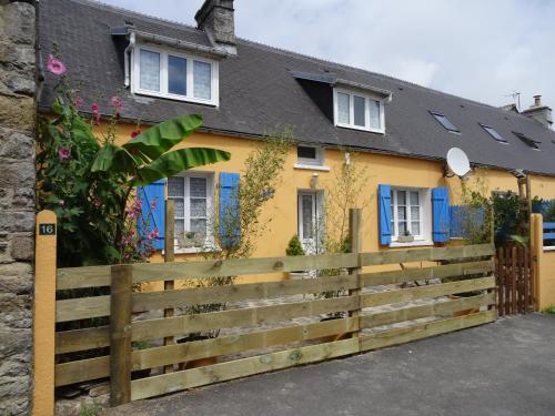 una casa amarilla con una valla de madera delante de ella en Gîtes Rose des Sables en Surtainville