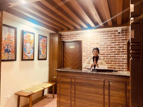 Una donna è in piedi dietro un bancone in una stanza di Harsha Boutique Hotel a Kathmandu